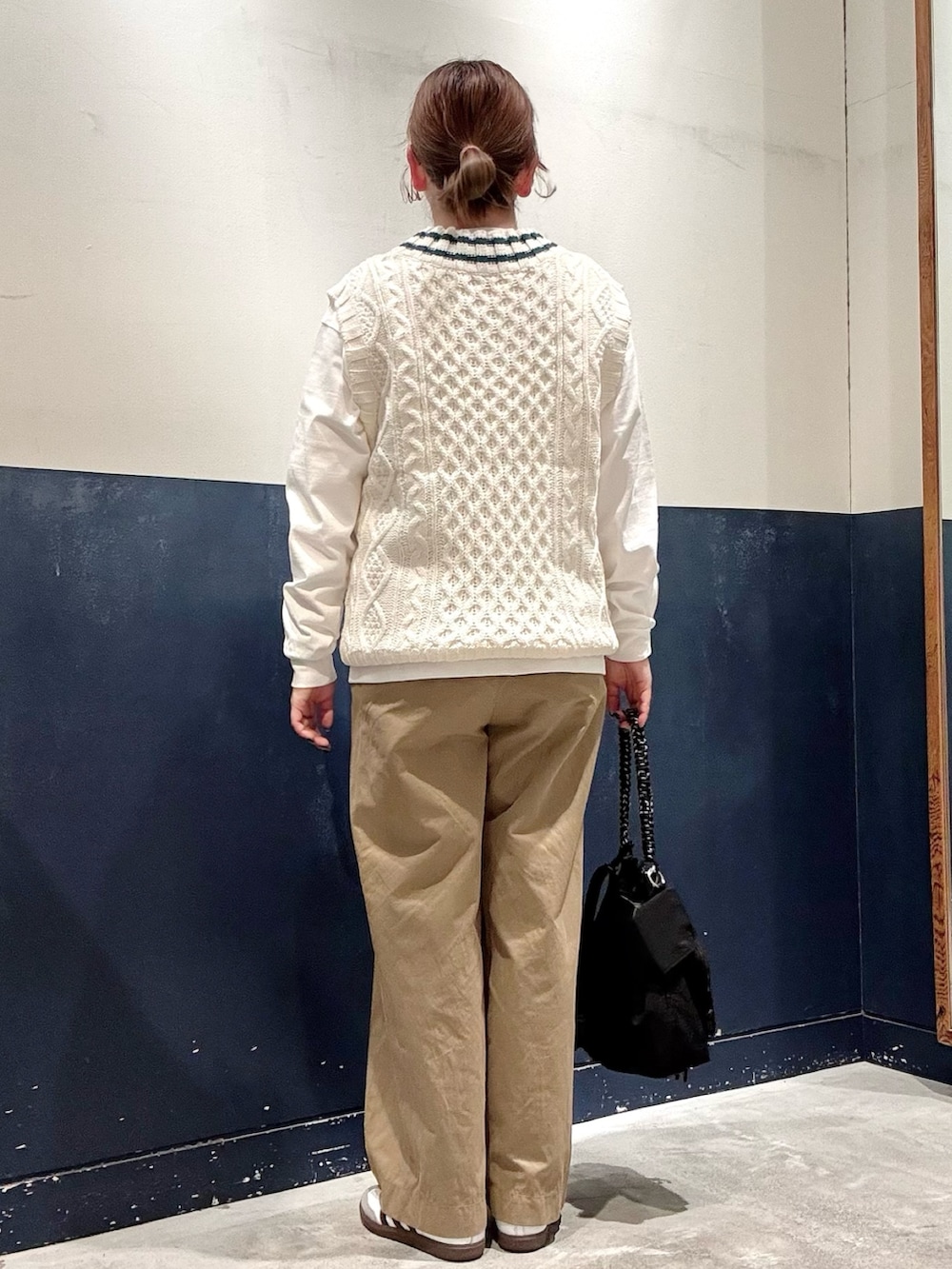 ベージュ系のデニムパンツ、ブラック系のトートバッグ、ホワイト系のベストを着用したレディースの秋コーディネートの3枚目の写真