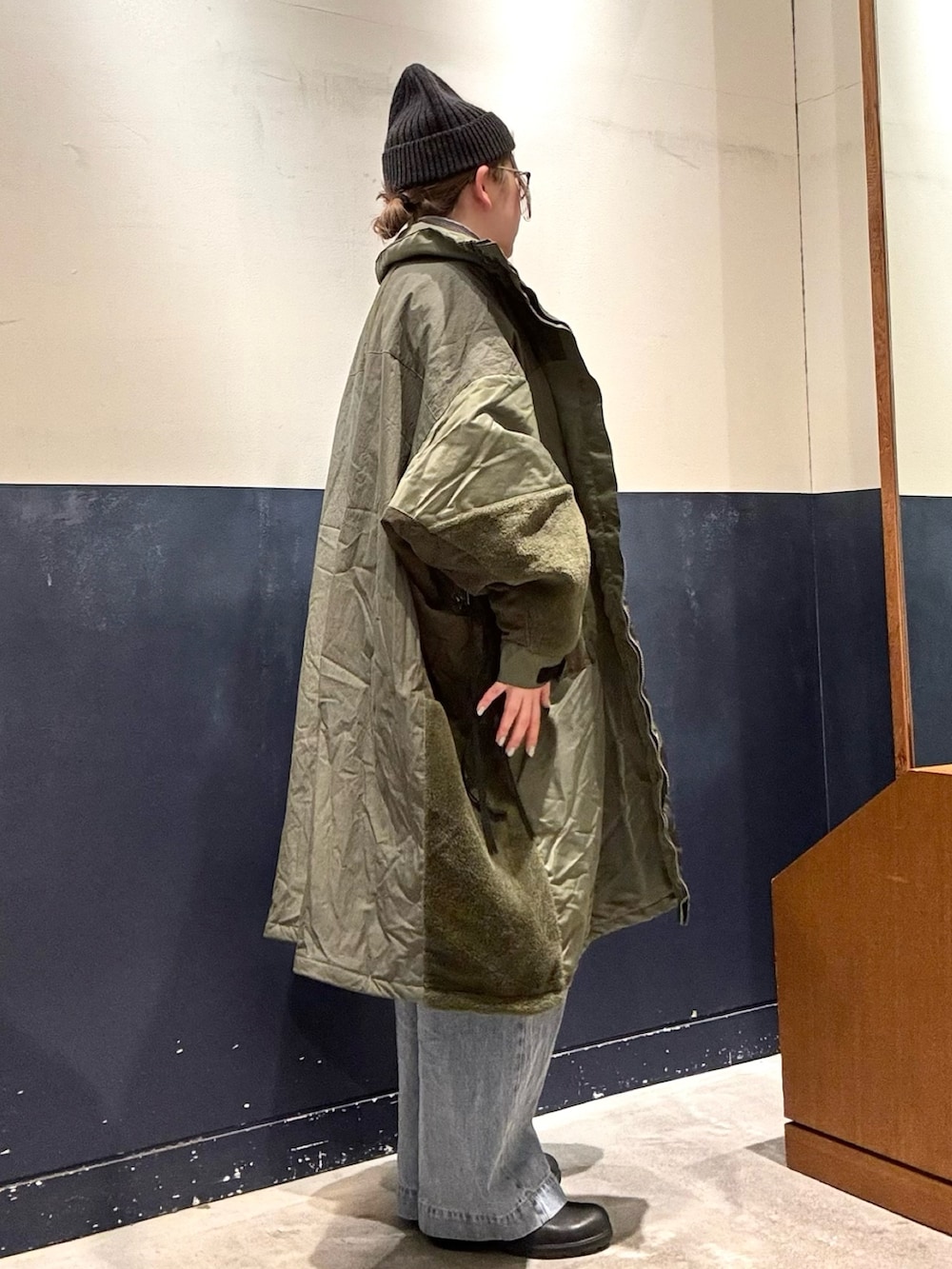 ブルー系のデニムパンツ、グリーン系のモッズコート、グレー系のニット/セーターを着用したレディースの冬コーディネートの2枚目の写真