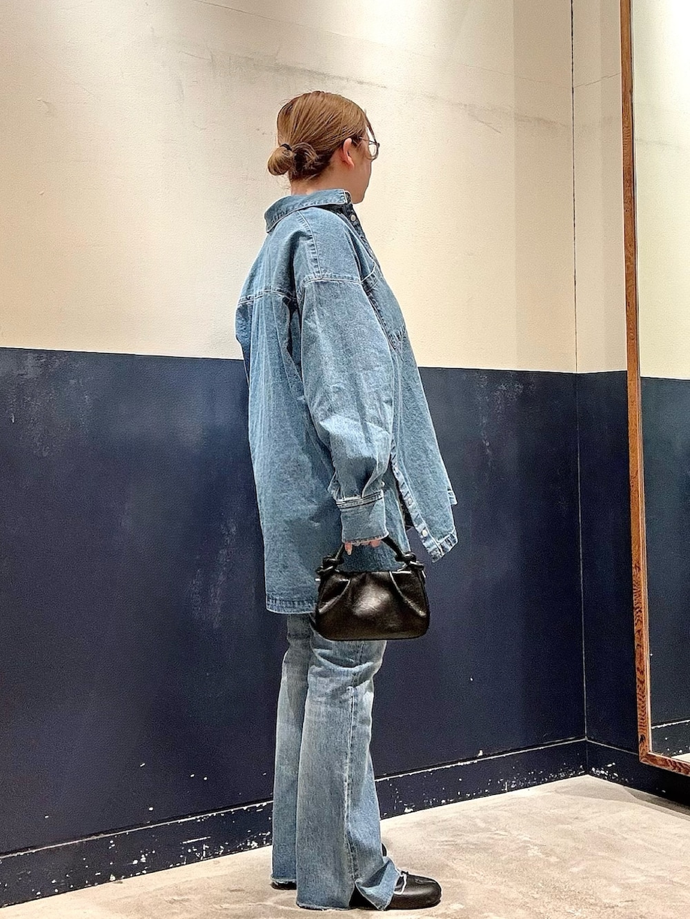 ブルー系のデニムパンツ、ブラック系のショルダーバッグ、ブルー系のデニムジャケットを着用したレディースの冬コーディネートの2枚目の写真