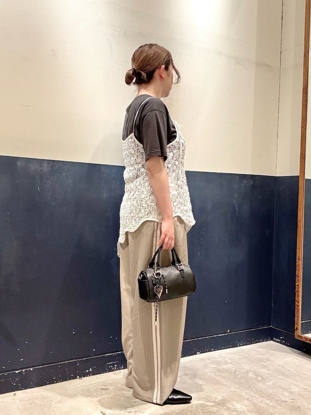 ブラック系のパンプス、ベージュ系のスラックス、ホワイト系のタンクトップを着用したレディースの春コーディネートの2枚目の写真