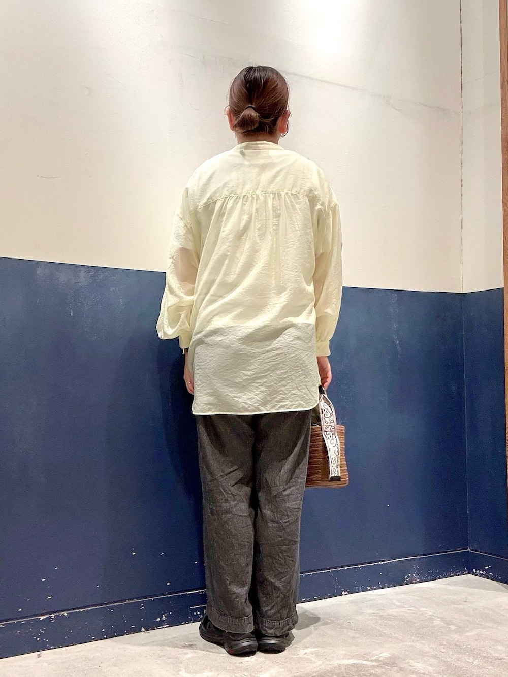 ブラウン系のトートバッグ、ブラック系のデニムパンツ、ホワイト系のTシャツ/カットソーを着用したレディースの夏コーディネートの3枚目の写真