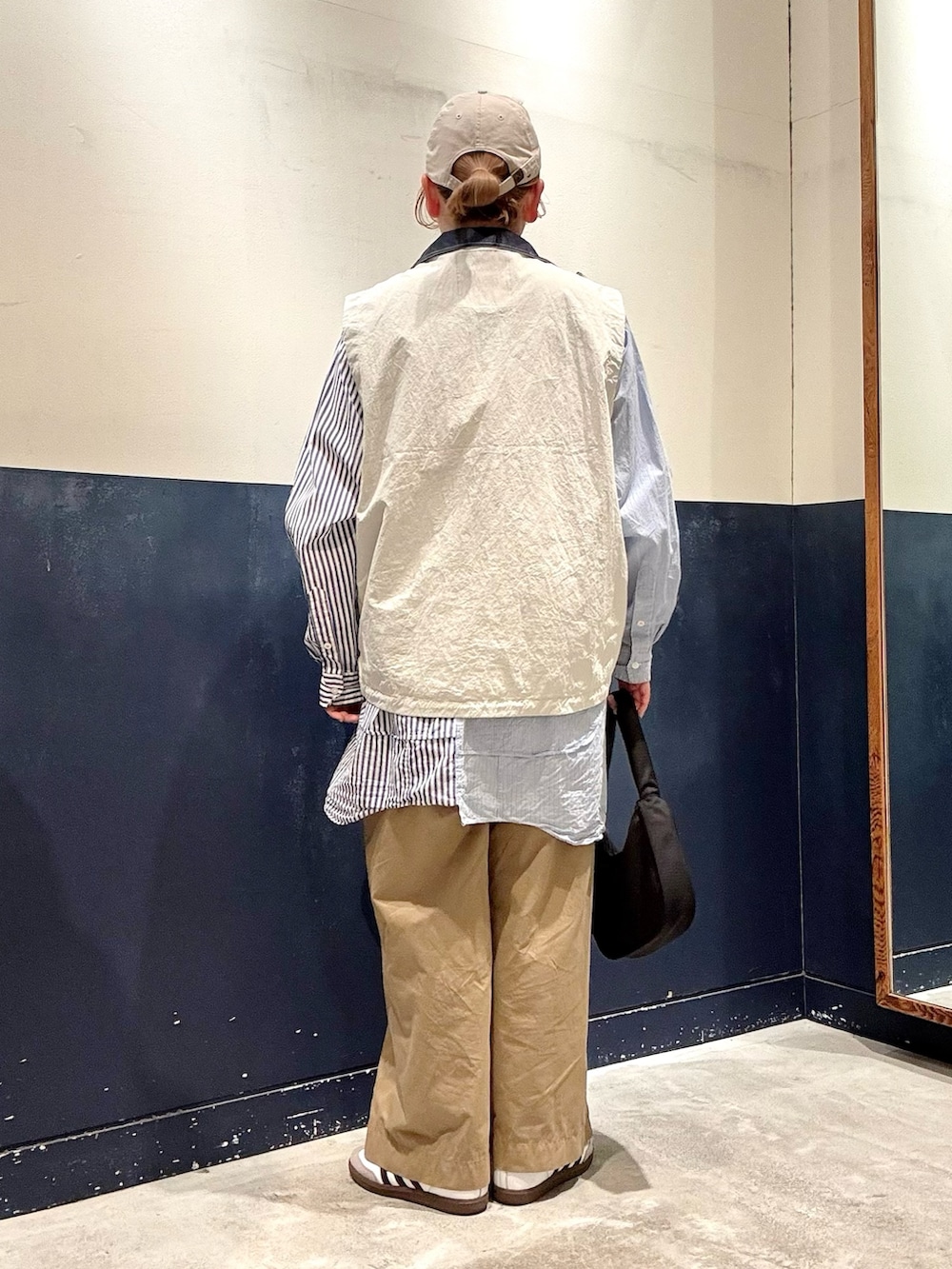 グレー系のベスト、ブルー系のシャツ/ブラウス、ブラック系のショルダーバッグを着用したレディースの春コーディネートの3枚目の写真