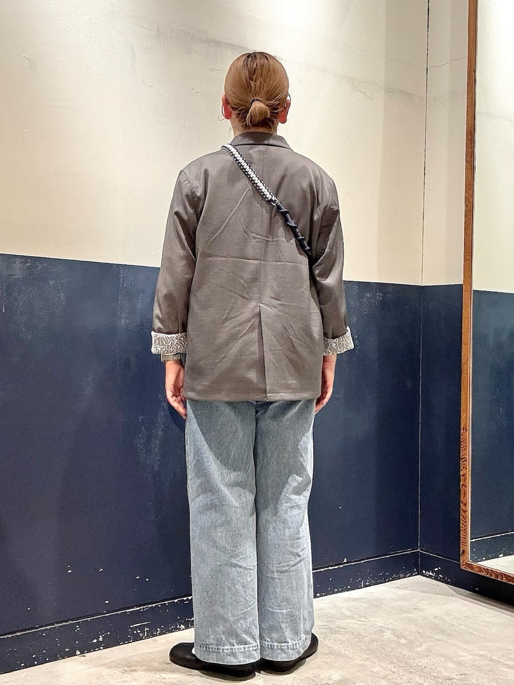 ブルー系のデニムパンツ、グレー系のテーラードジャケット、ブラック系のショルダーバッグを着用したレディースの春コーディネートの3枚目の写真