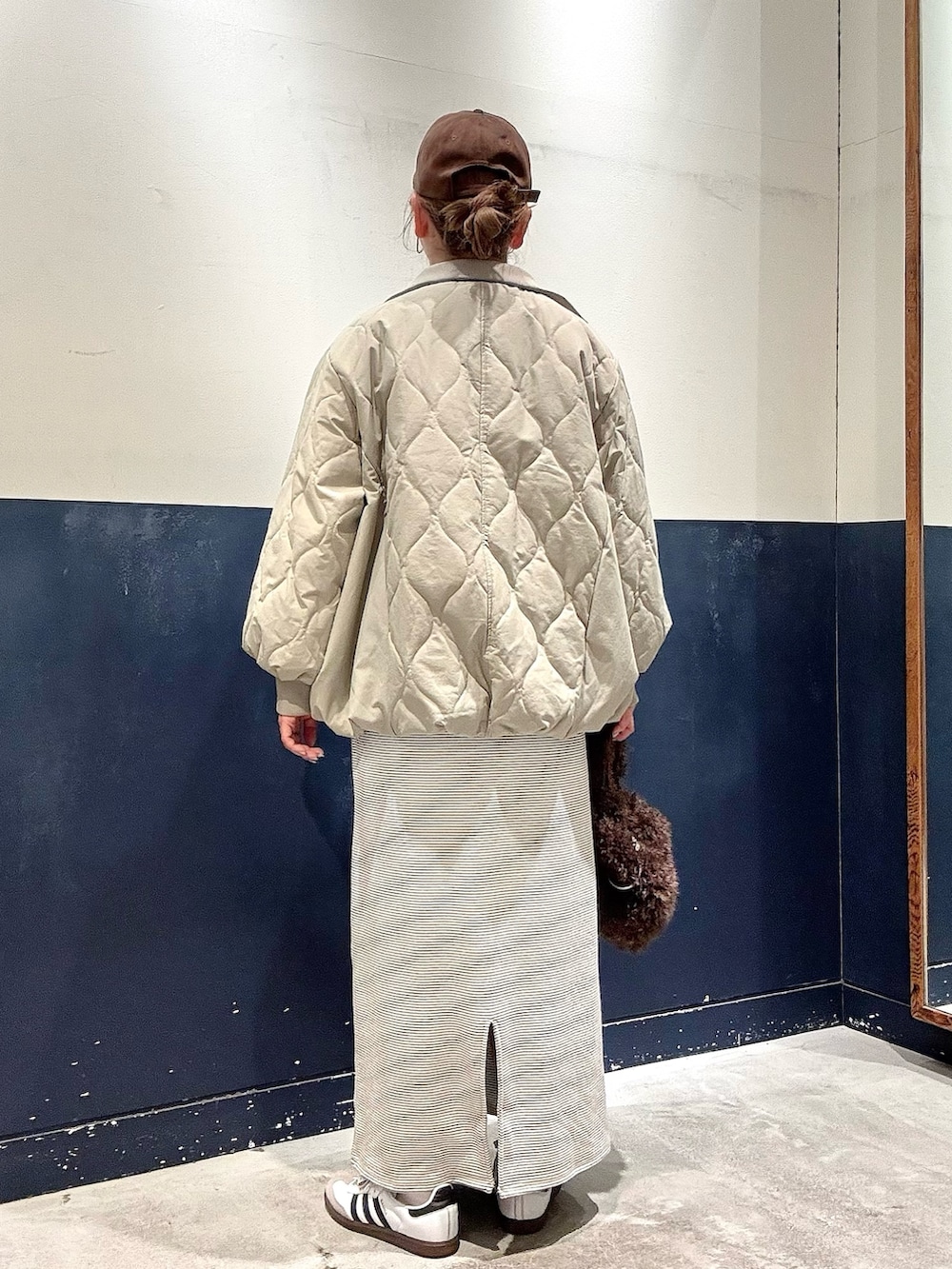 ブラウン系のトートバッグ、グリーン系のブルゾン、ホワイト系のワンピースを着用したレディースの冬コーディネートの3枚目の写真