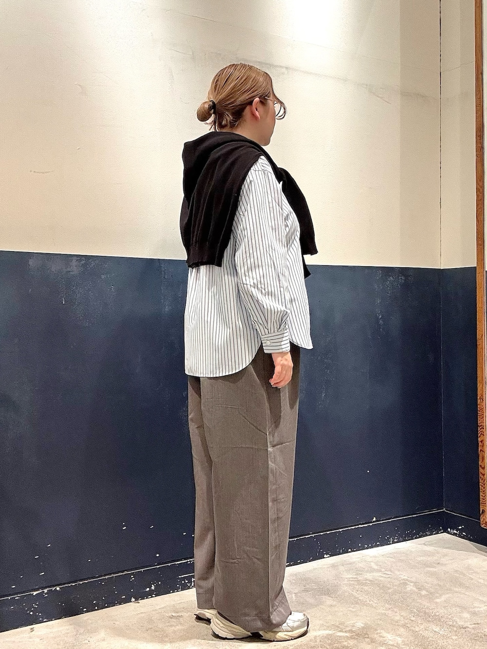 グレー系のデニムパンツ、ブルー系のシャツ/ブラウス、ブラック系のニット/セーターを着用したレディースの春コーディネートの2枚目の写真