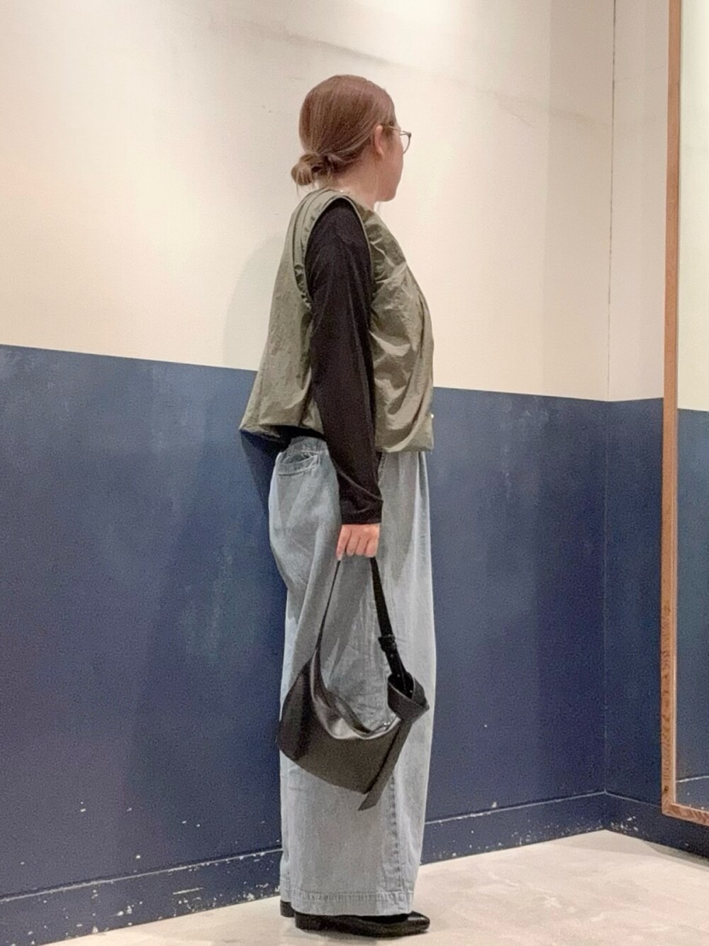 ブラック系のパンプス、ブルー系のデニムパンツ、ブラック系のショルダーバッグを着用したレディースの夏コーディネートの2枚目の写真