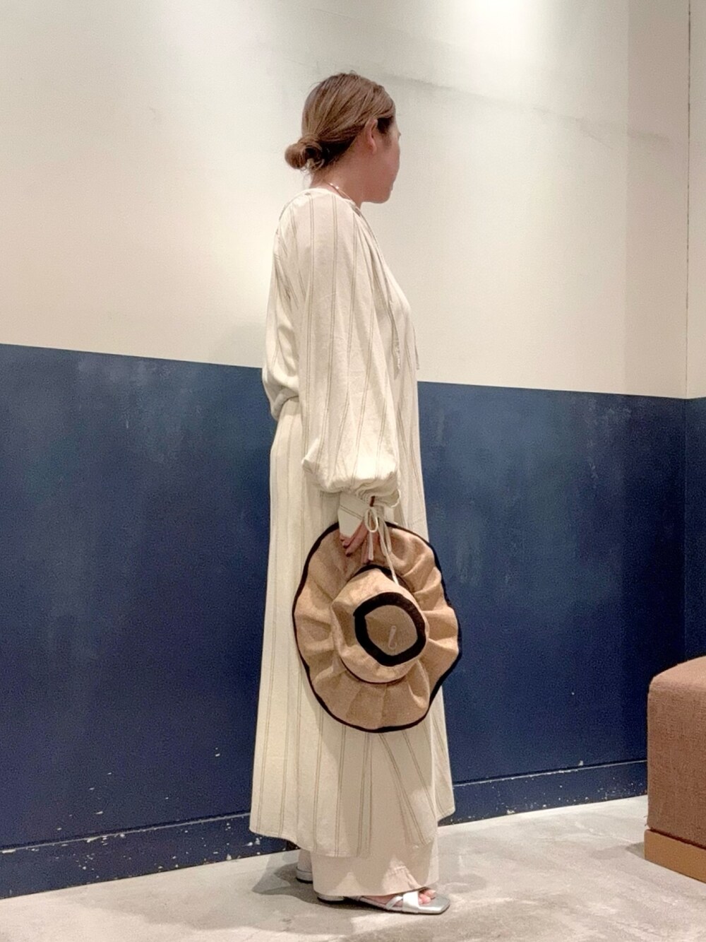 イエロー系のタンクトップ、ベージュ系のワンピース、ホワイト系のデニムパンツを着用したレディースの夏コーディネートの2枚目の写真