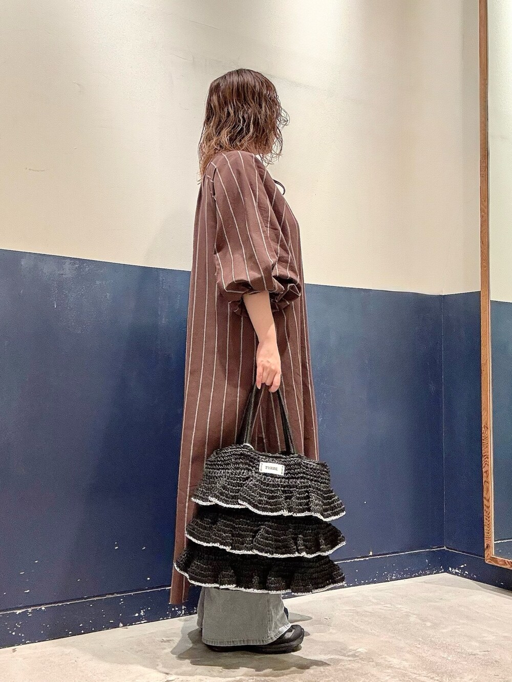 ブラウン系のワンピース、ブラック系のトートバッグ、ブルー系のデニムパンツを着用したレディースの夏コーディネートの2枚目の写真