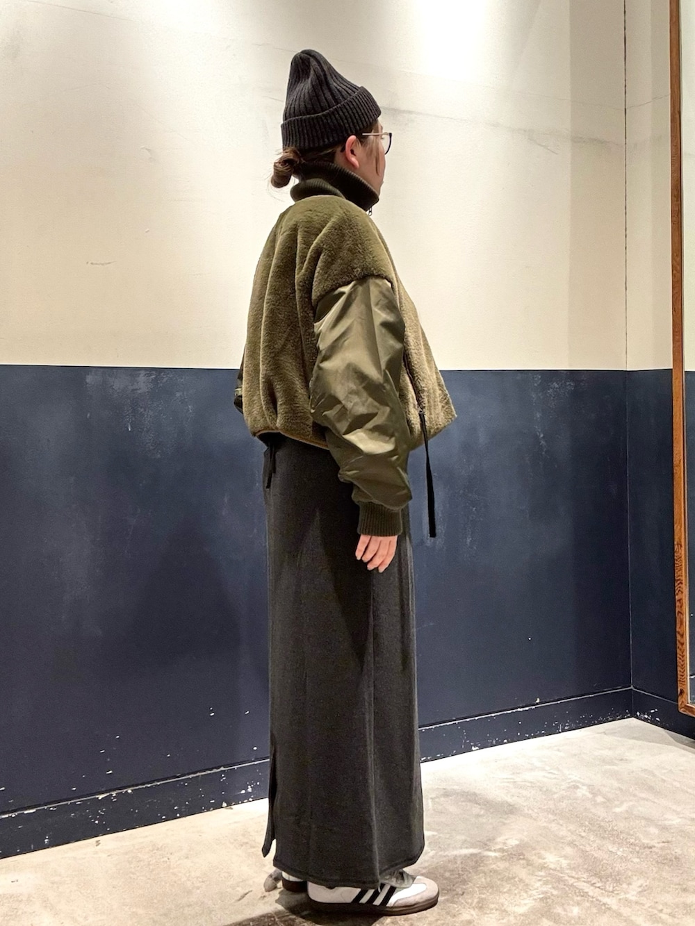 グリーン系のミリタリージャケット、グレー系のワンピースを着用したレディースの冬コーディネートの2枚目の写真