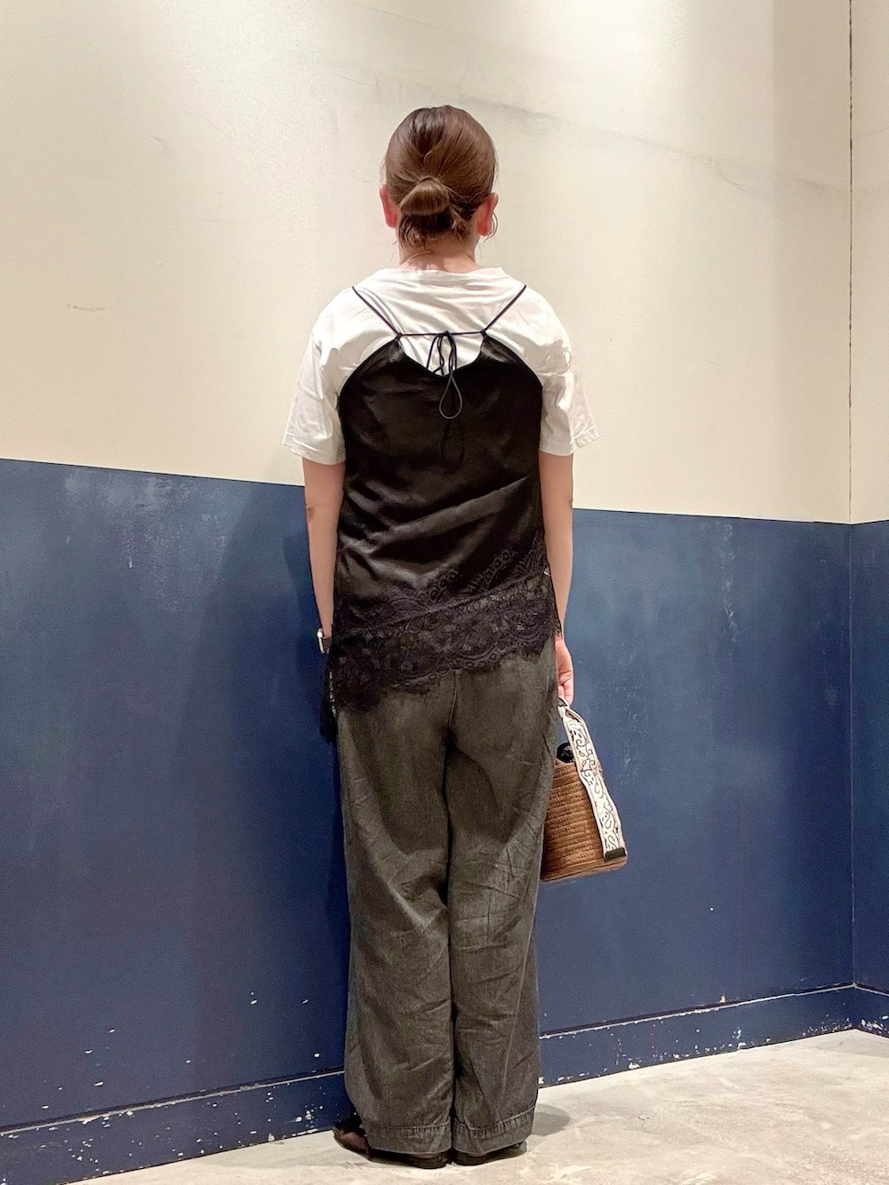 ブラウン系のトートバッグ、ブラック系のデニムパンツ、ブラック系のチュニックを着用したレディースの夏コーディネートの3枚目の写真