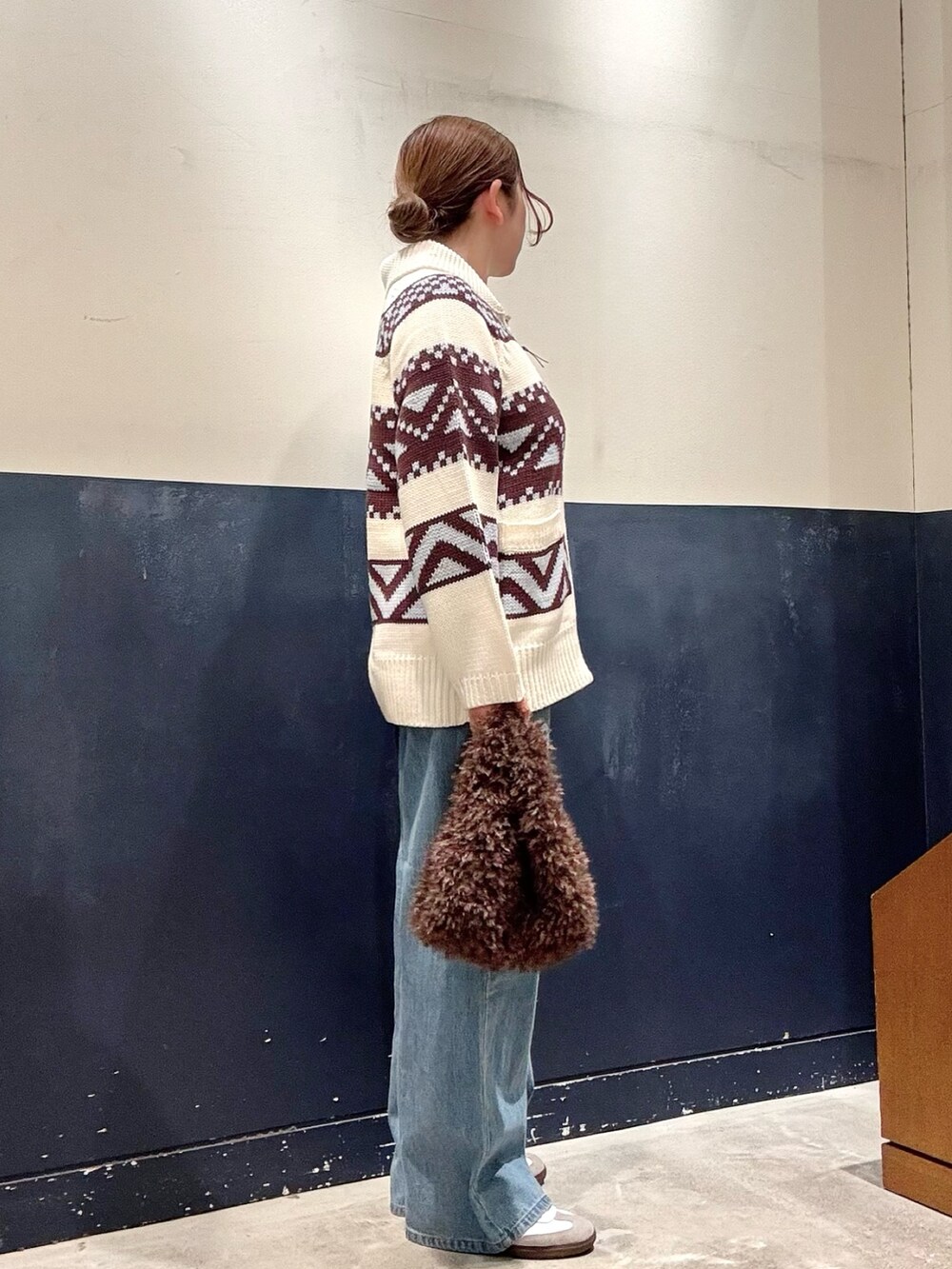 ブラウン系のトートバッグ、ブルー系のデニムパンツ、ホワイト系のカーディガン/ボレロを着用したレディースの秋コーディネートの2枚目の写真