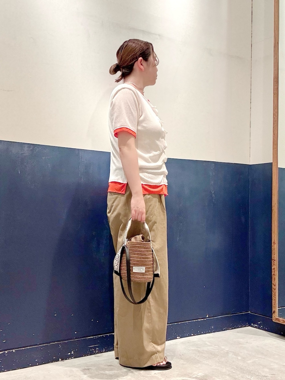 ブラウン系のトートバッグ、ベージュ系のデニムパンツ、イエロー系のサンダルを着用したレディースの夏コーディネートの2枚目の写真