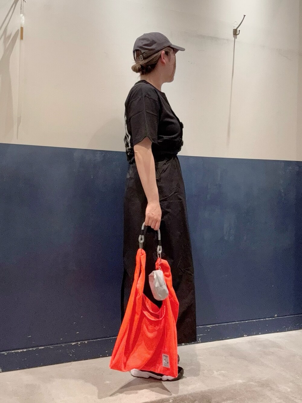 ブラック系のTシャツ/カットソー、オレンジ系のトートバッグ、ブラック系のスカートを着用したレディースの春コーディネートの2枚目の写真