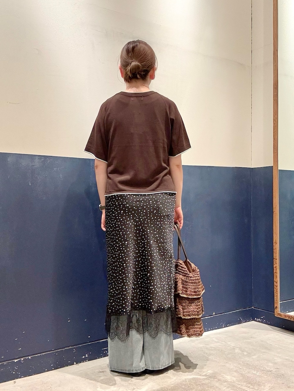 ブラウン系のトートバッグ、ブラック系のパンプス、ブルー系のデニムパンツを着用したレディースの夏コーディネートの3枚目の写真