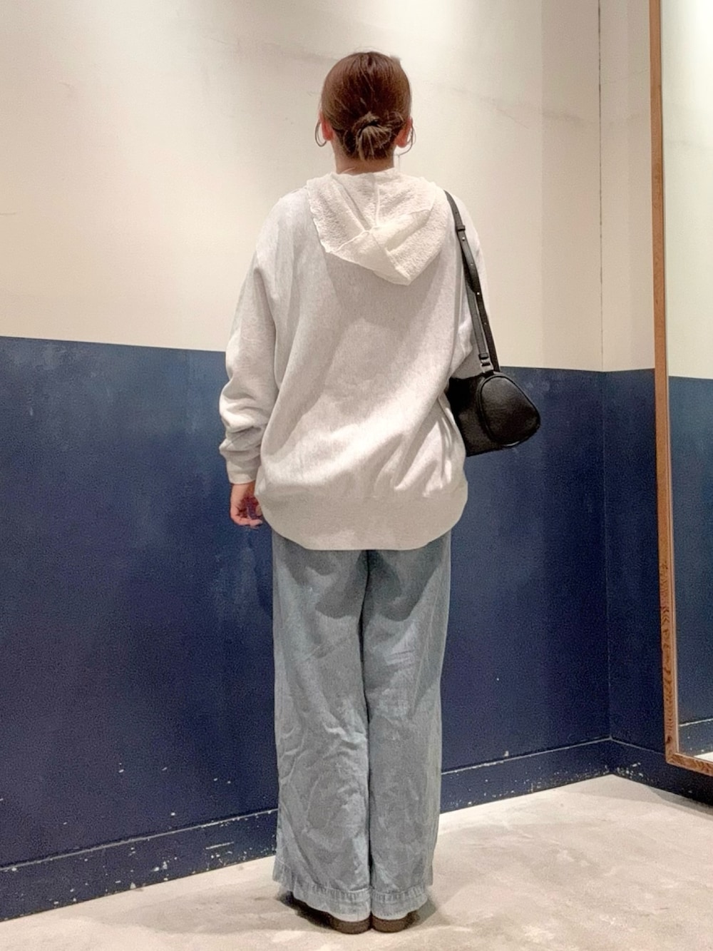 ブルー系のデニムパンツ、ブラック系のショルダーバッグ、グレー系のスウェットを着用したレディースの秋コーディネートの3枚目の写真