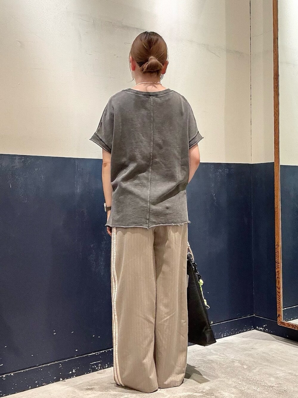 ブラック系のパンプス、ブラック系のショルダーバッグ、ベージュ系のスラックスを着用したレディースの春コーディネートの3枚目の写真