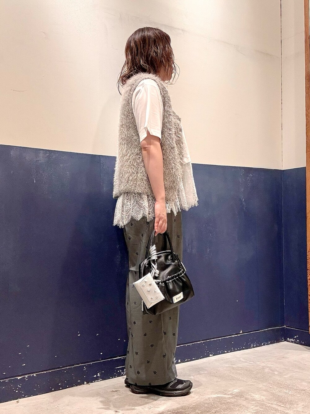 グレー系のスラックス、ブラック系のショルダーバッグ、ホワイト系のTシャツ/カットソーを着用したレディースの夏コーディネートの2枚目の写真