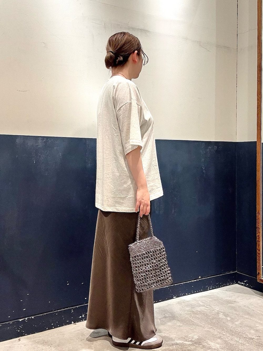 グレー系のスカート、グレー系のショルダーバッグ、ホワイト系のTシャツ/カットソーを着用したレディースの春コーディネートの2枚目の写真