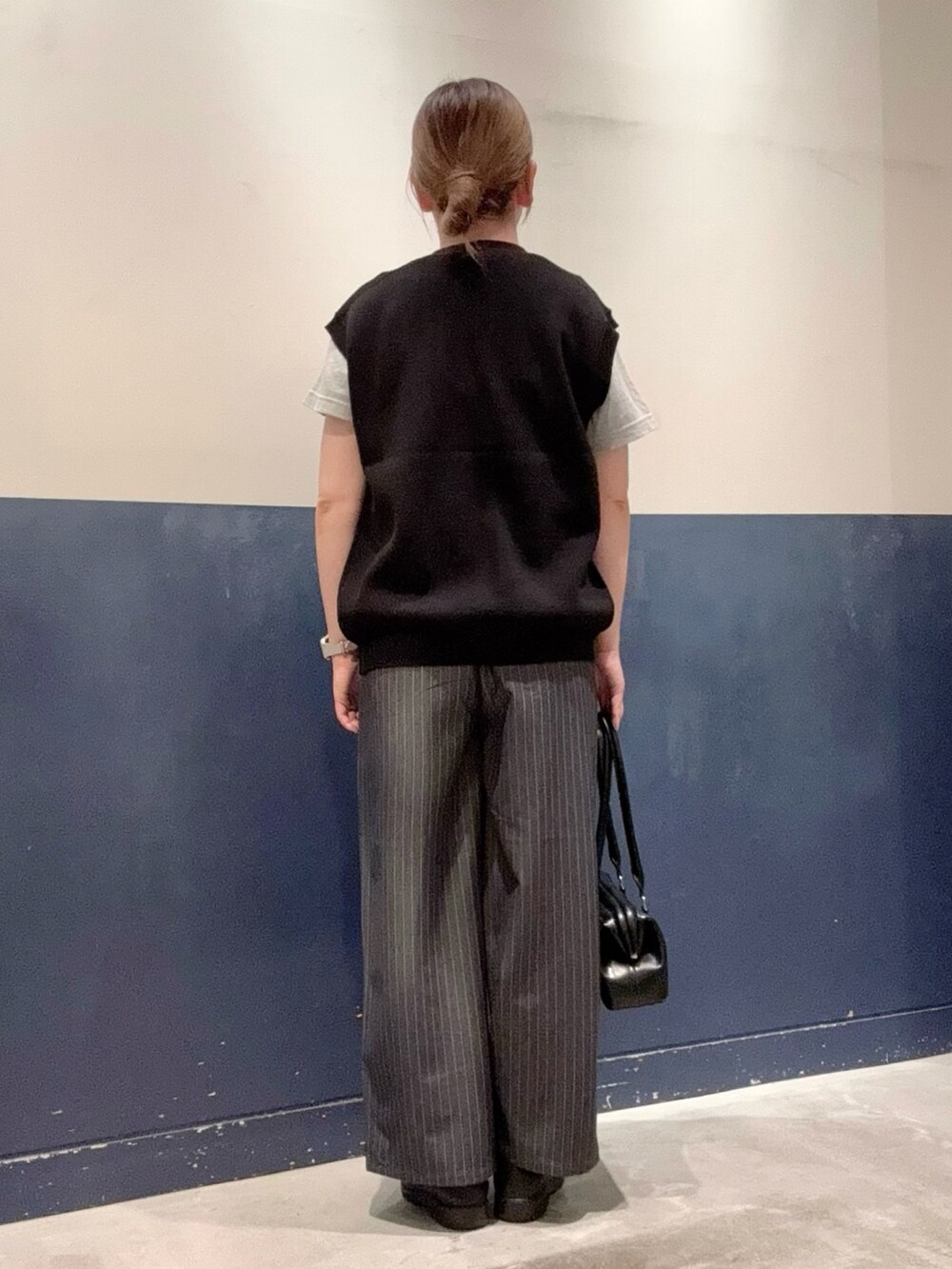 ブラック系のニット/セーター、グレー系のスラックス、グレー系のTシャツ/カットソーを着用したレディースの夏コーディネートの3枚目の写真