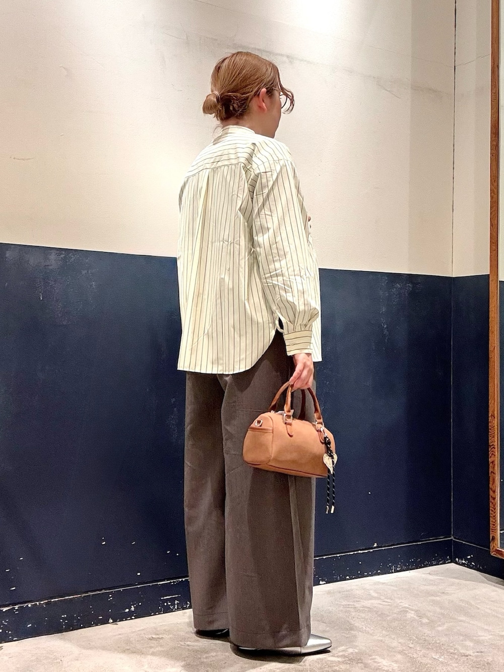 イエロー系のシャツ/ブラウス、シルバー系のパンプス、グレー系のデニムパンツを着用したレディースの冬コーディネートの2枚目の写真