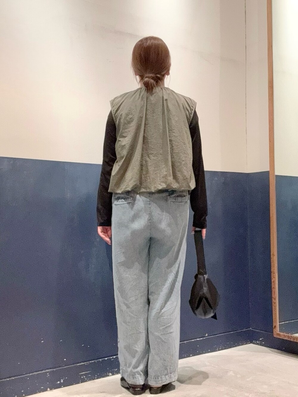 ブラック系のパンプス、ブルー系のデニムパンツ、ブラック系のショルダーバッグを着用したレディースの夏コーディネートの3枚目の写真