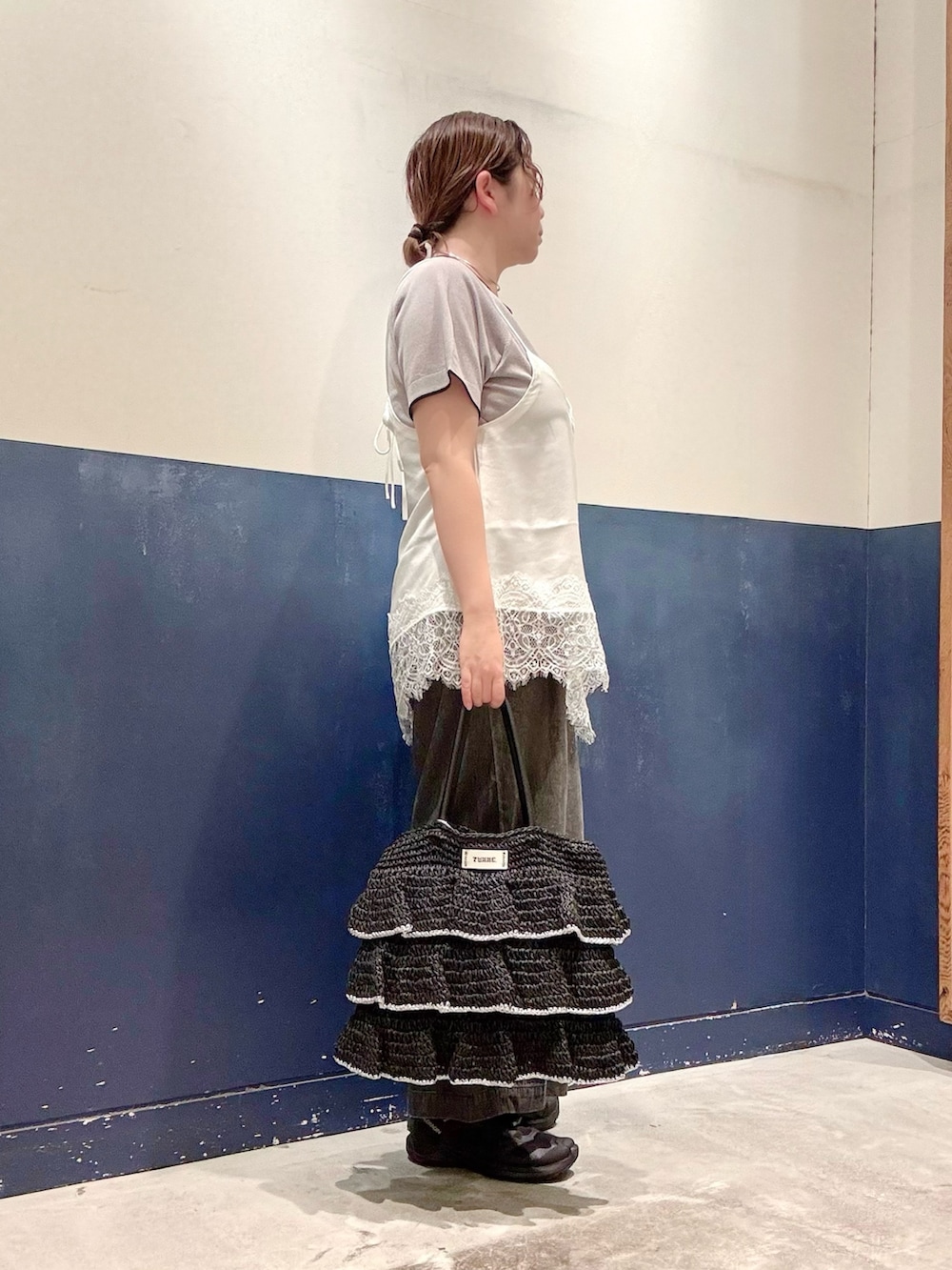 ブラック系のデニムパンツ、ブラック系のトートバッグ、ホワイト系のチュニックを着用したレディースの夏コーディネートの2枚目の写真