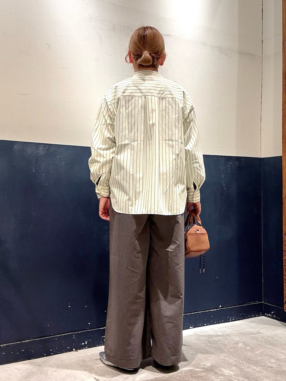 イエロー系のシャツ/ブラウス、シルバー系のパンプス、グレー系のデニムパンツを着用したレディースの冬コーディネートの3枚目の写真