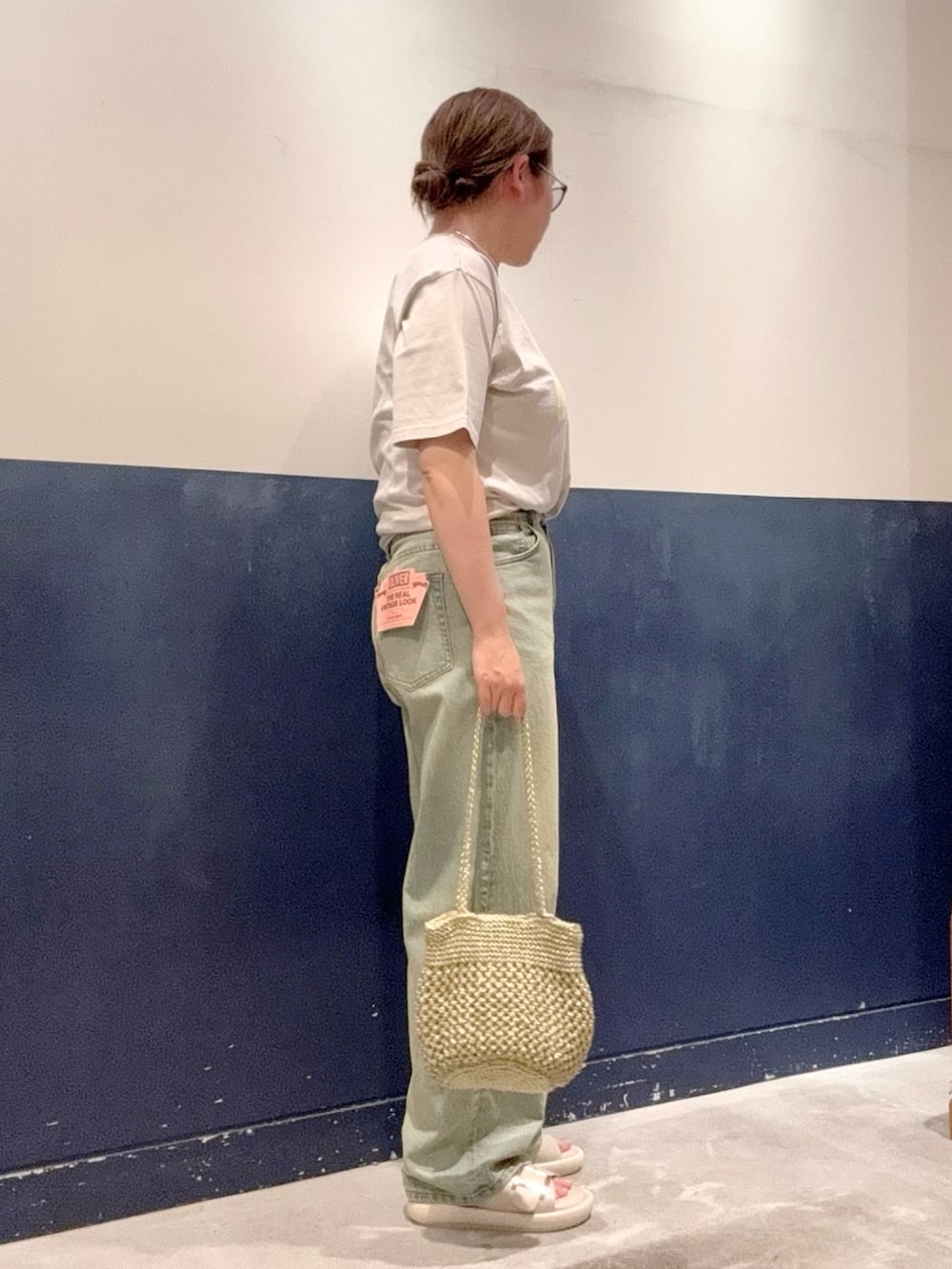 ブルー系のデニムパンツ、ゴールド系のトートバッグ、グレー系のTシャツ/カットソーを着用したレディースの夏コーディネートの2枚目の写真