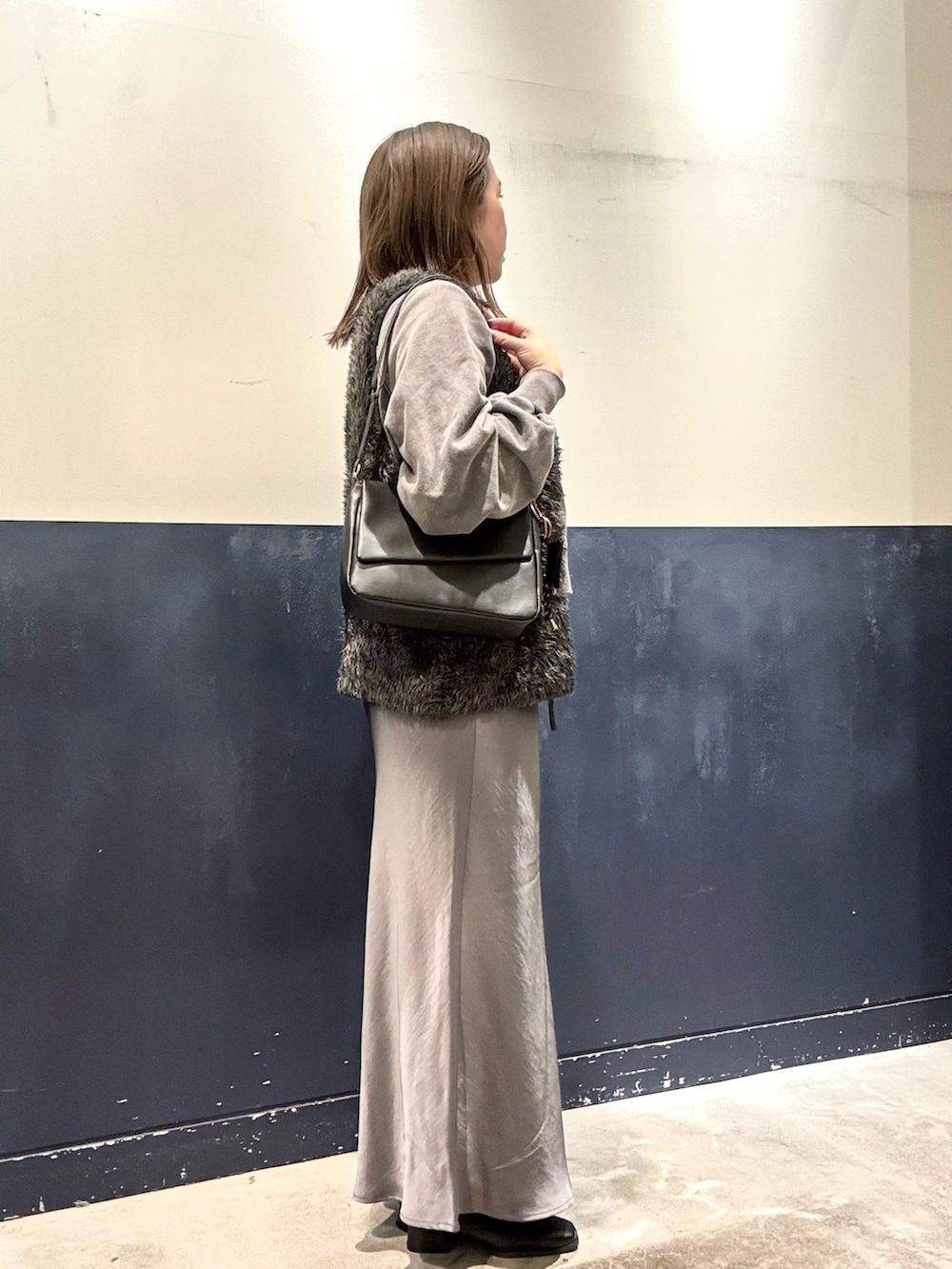 グレー系のスウェット、グレー系のスカート、ブラック系のショルダーバッグを着用したレディースの冬コーディネートの2枚目の写真