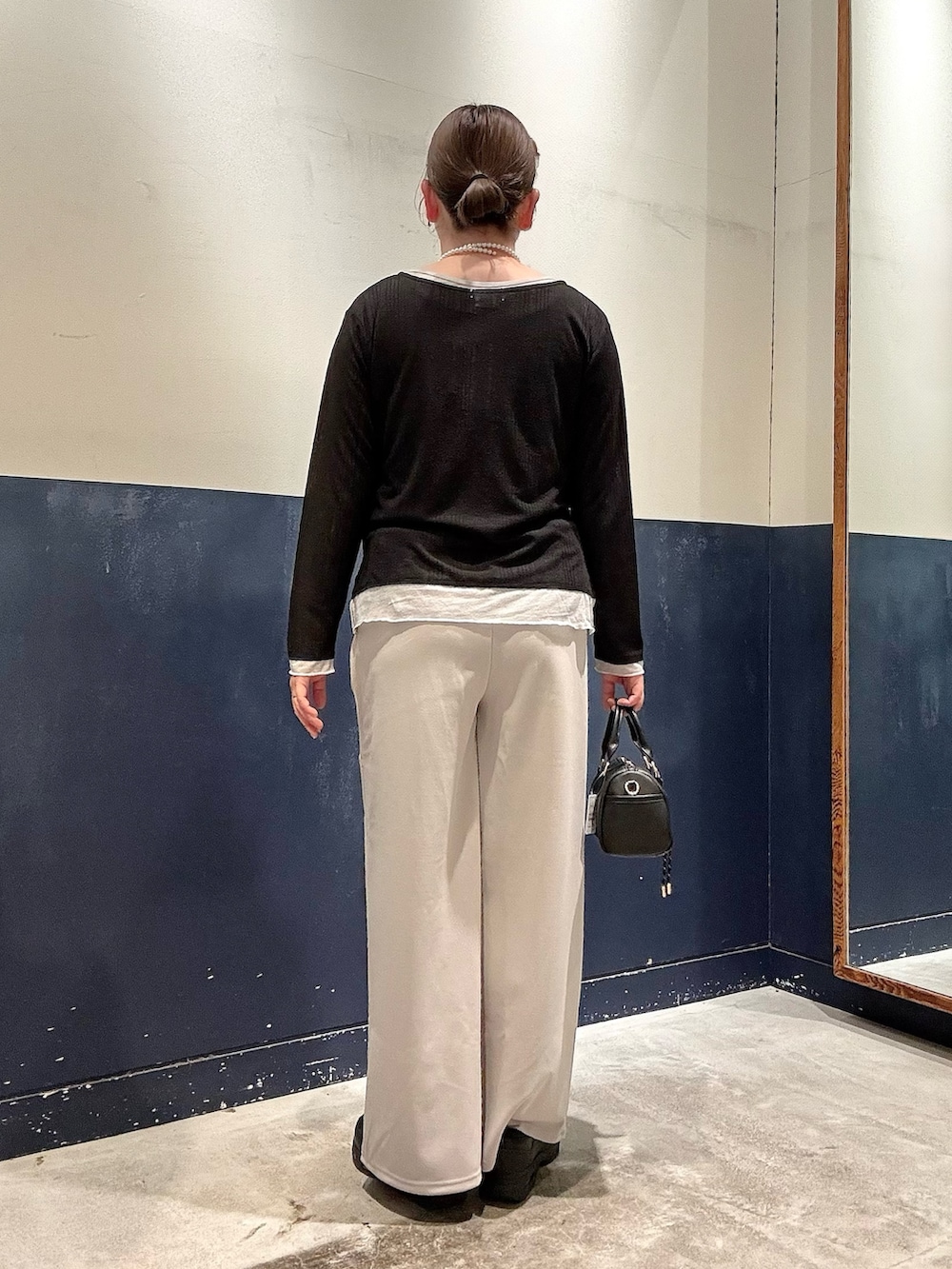 グレー系のスラックス、ブラック系のショルダーバッグ、ブラック系のカーディガン/ボレロを着用したレディースの春コーディネートの3枚目の写真