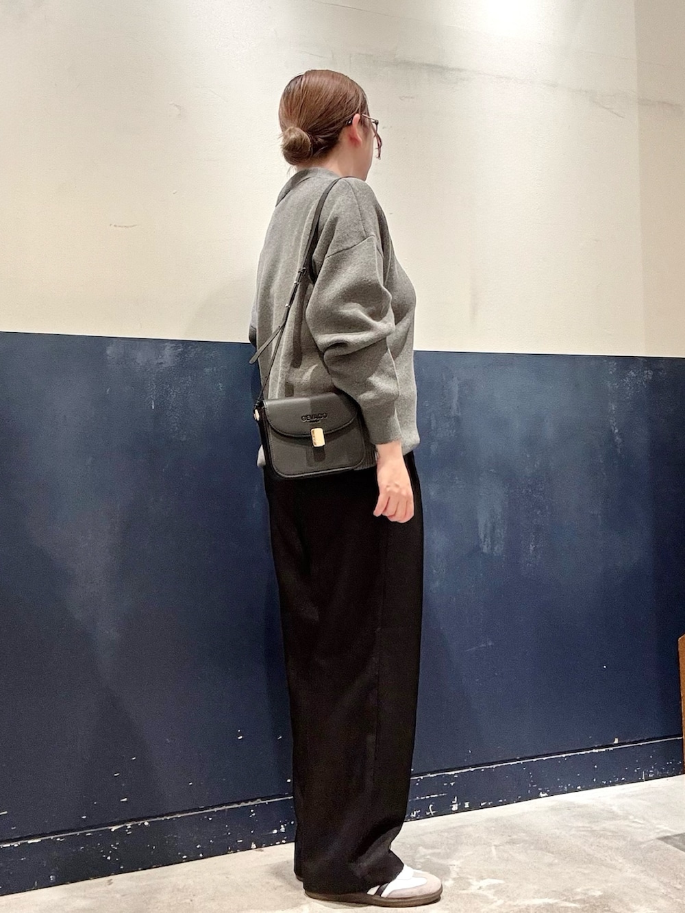 ブラック系のスラックス、グレー系のニット/セーター、ブラック系のショルダーバッグを着用したレディースの秋コーディネートの2枚目の写真