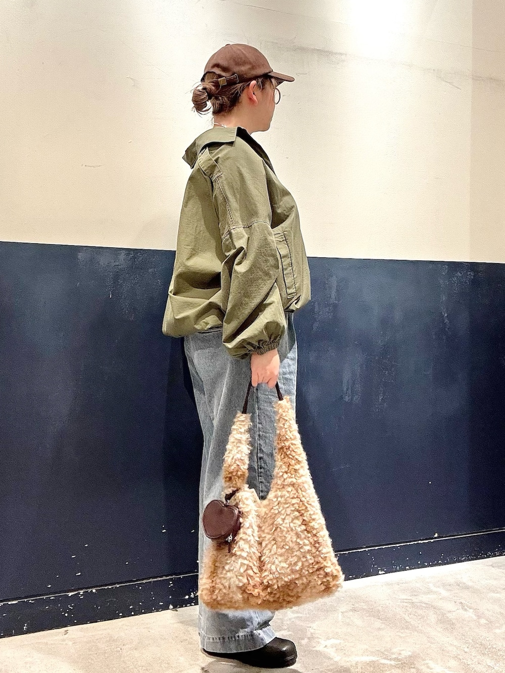 ベージュ系のトートバッグ、ホワイト系のTシャツ/カットソー、グリーン系のブルゾンを着用したレディースの冬コーディネートの2枚目の写真