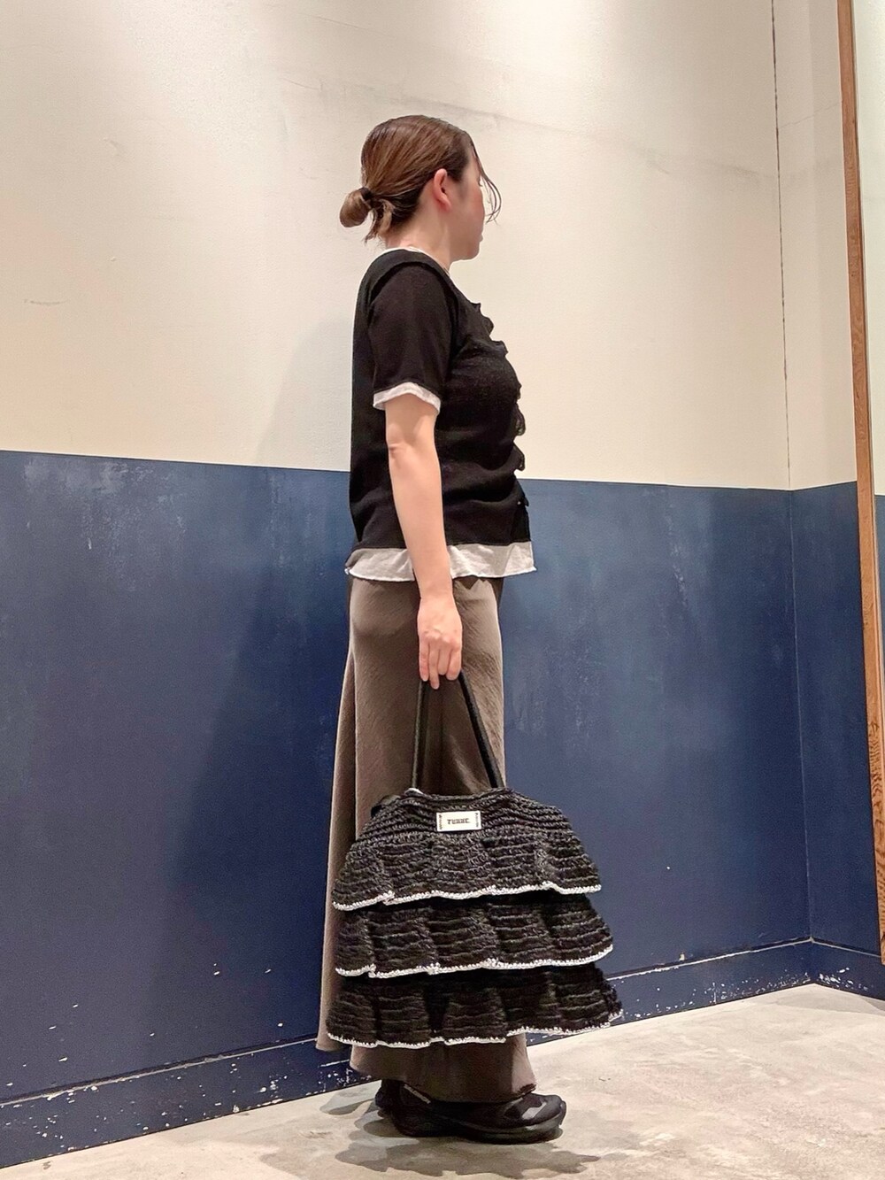 ブラック系のトートバッグ、グレー系のスカート、ブラック系のカーディガン/ボレロを着用したレディースの夏コーディネートの2枚目の写真