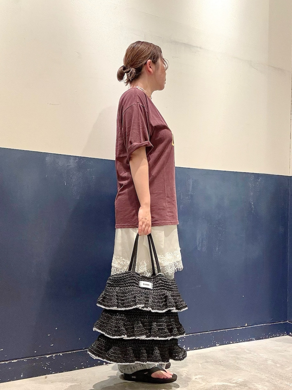 ブラック系のトートバッグ、ブルー系のデニムパンツ、ホワイト系のスカートを着用したレディースの夏コーディネートの2枚目の写真