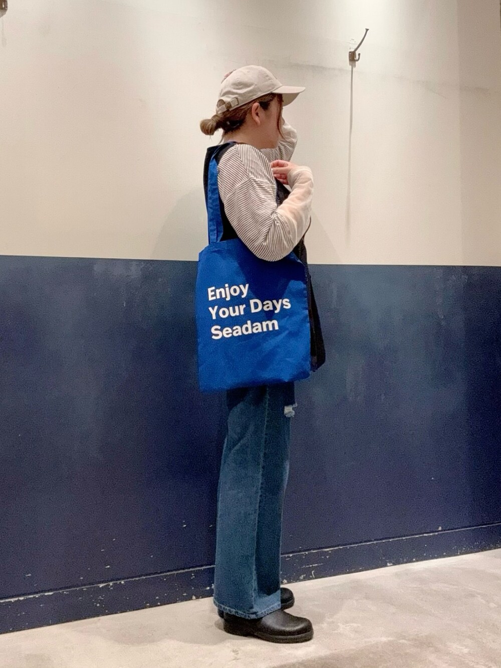 ブラック系のベスト、ホワイト系のTシャツ/カットソー、ブルー系のトートバッグを着用したレディースの夏コーディネートの2枚目の写真