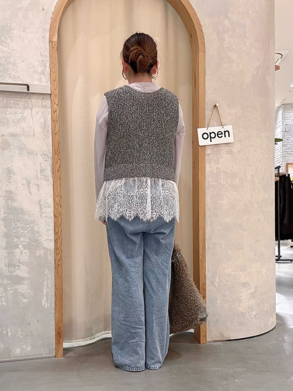 ブラック系のパンプス、ブルー系のデニムパンツ、グレー系のショルダーバッグを着用したレディースの秋コーディネートの3枚目の写真