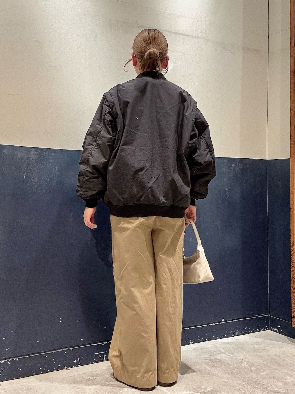 ベージュ系のデニムパンツ、グレー系のショルダーバッグ、ブラック系のMA-1を着用したレディースの冬コーディネートの2枚目の写真