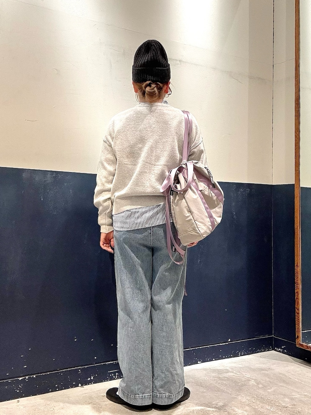 ブルー系のデニムパンツ、グレー系のトートバッグ、ホワイト系のニット/セーターを着用したレディースの冬コーディネートの3枚目の写真