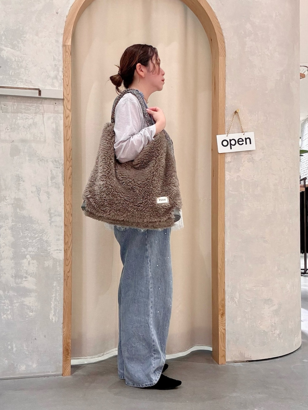 ブラック系のパンプス、ブルー系のデニムパンツ、グレー系のショルダーバッグを着用したレディースの秋コーディネートの2枚目の写真
