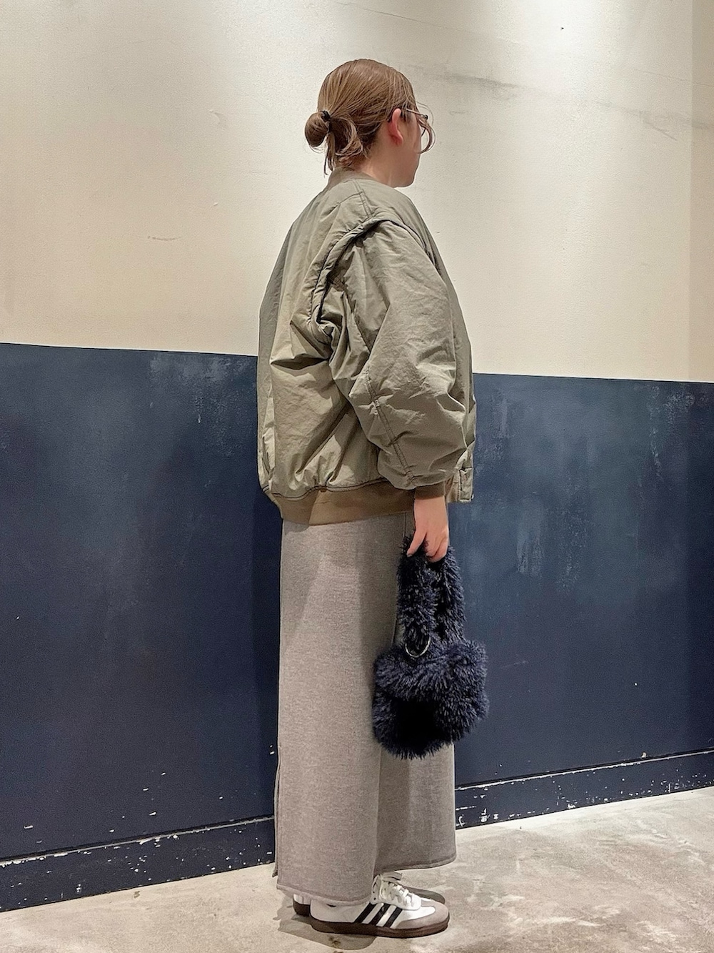 グレー系のワンピース、グリーン系のMA-1、ブルー系のトートバッグを着用したレディースの冬コーディネートの2枚目の写真