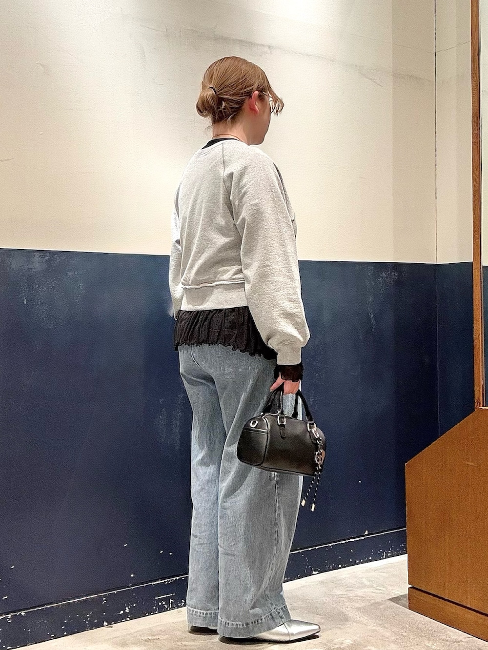 ブルー系のデニムパンツ、ブラック系のショルダーバッグ、シルバー系のパンプスを着用したレディースの冬コーディネートの2枚目の写真