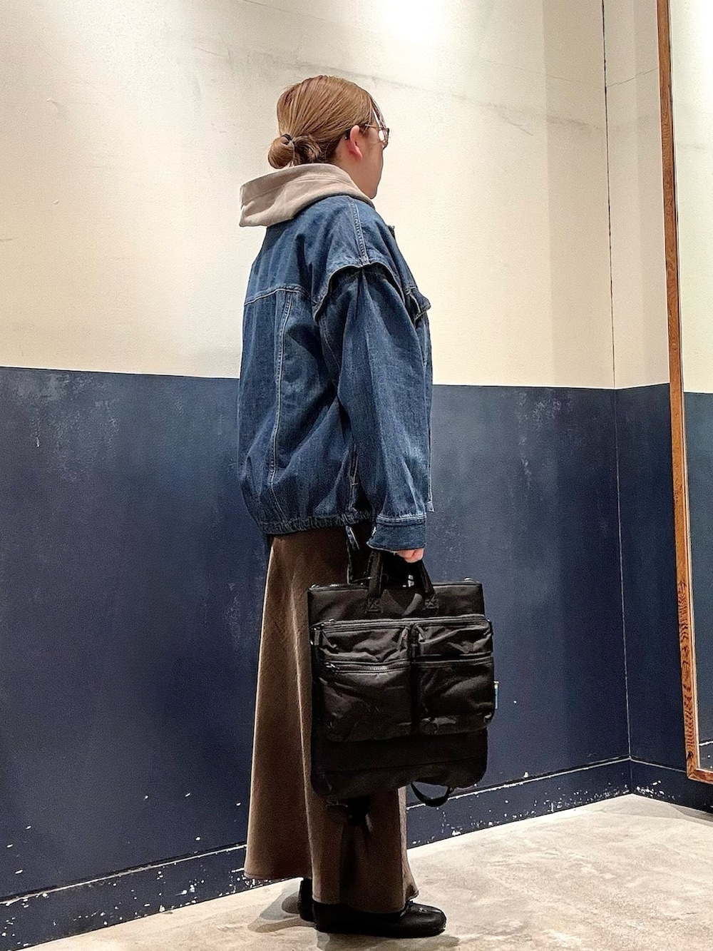 ブラック系のショルダーバッグ、グレー系のスカート、ブルー系のデニムジャケットを着用したレディースの冬コーディネートの2枚目の写真