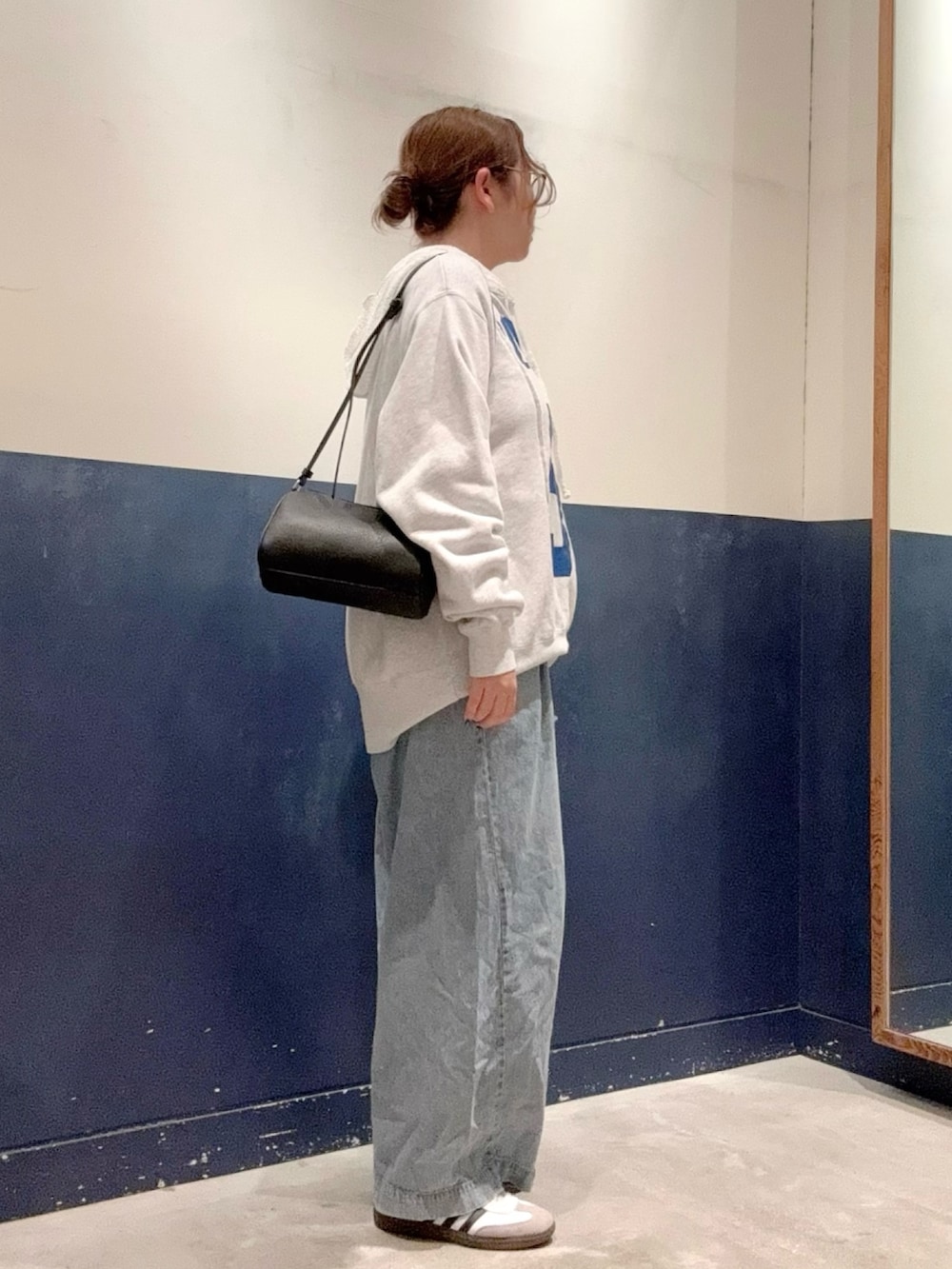 ブルー系のデニムパンツ、ブラック系のショルダーバッグ、グレー系のスウェットを着用したレディースの秋コーディネートの2枚目の写真