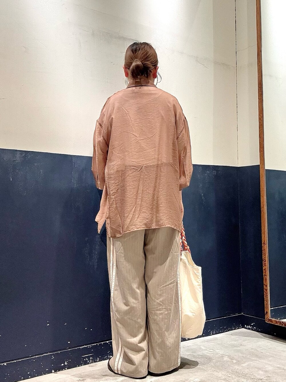 ホワイト系のトートバッグ、ベージュ系のスラックス、ホワイト系のTシャツ/カットソーを着用したレディースの夏コーディネートの3枚目の写真