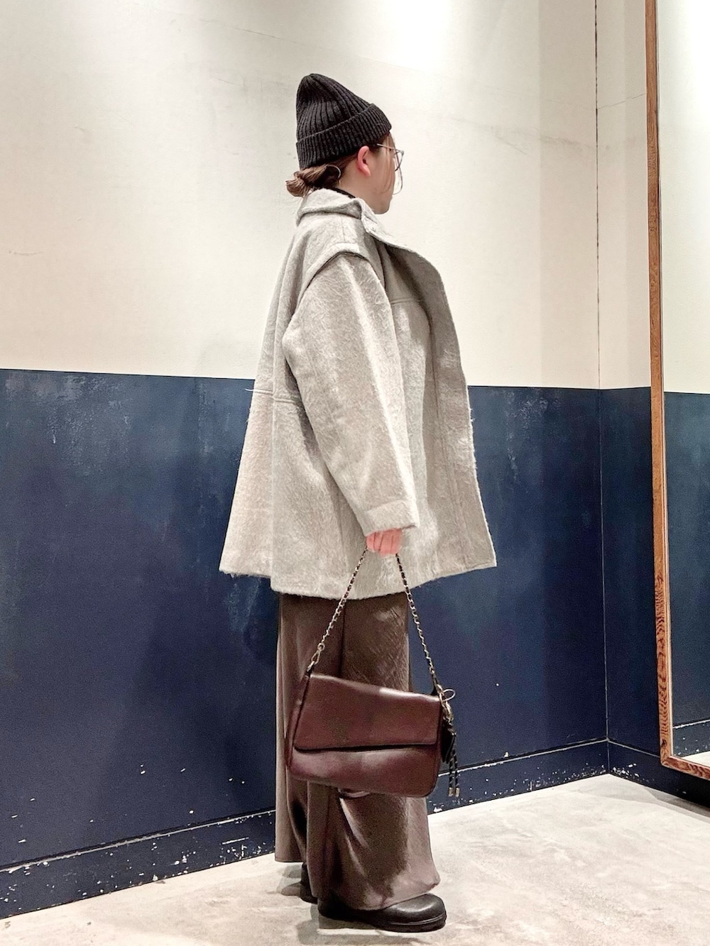 ブラック系のニット/セーター、ブラウン系のショルダーバッグ、グレー系のスカートを着用したレディースの冬コーディネートの2枚目の写真