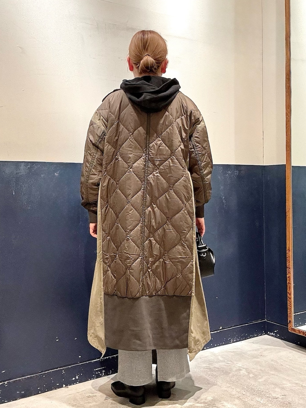 ブラック系のパーカー、グリーン系のモッズコート、ブラック系のブーツを着用したレディースの冬コーディネートの3枚目の写真