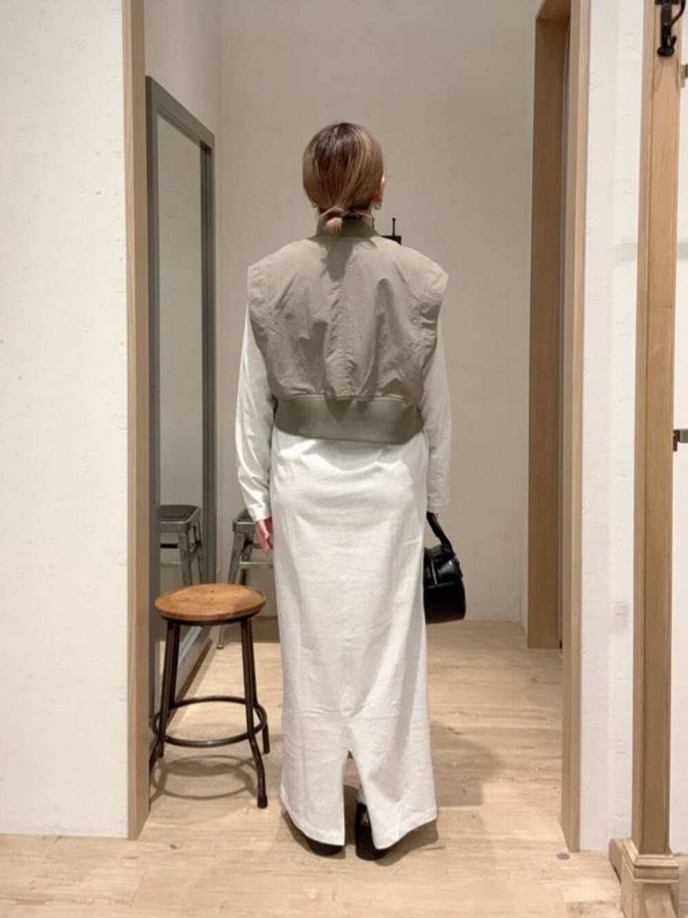 グリーン系のベスト、グレー系のワンピース、ブラック系のショルダーバッグを着用したレディースの春コーディネートの3枚目の写真