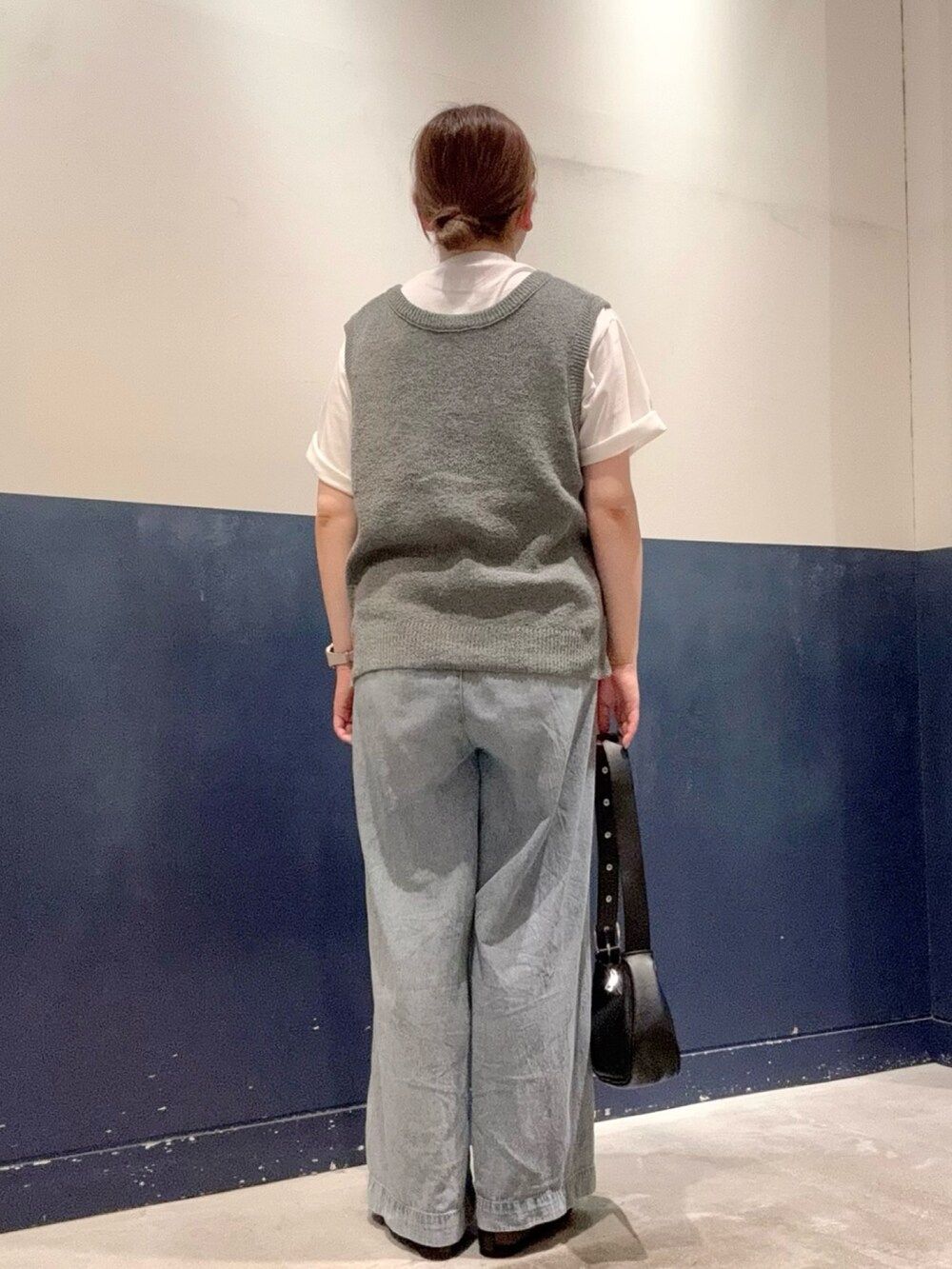 ブラック系のトートバッグ、ブルー系のデニムパンツ、グレー系のベストを着用したレディースの夏コーディネートの3枚目の写真