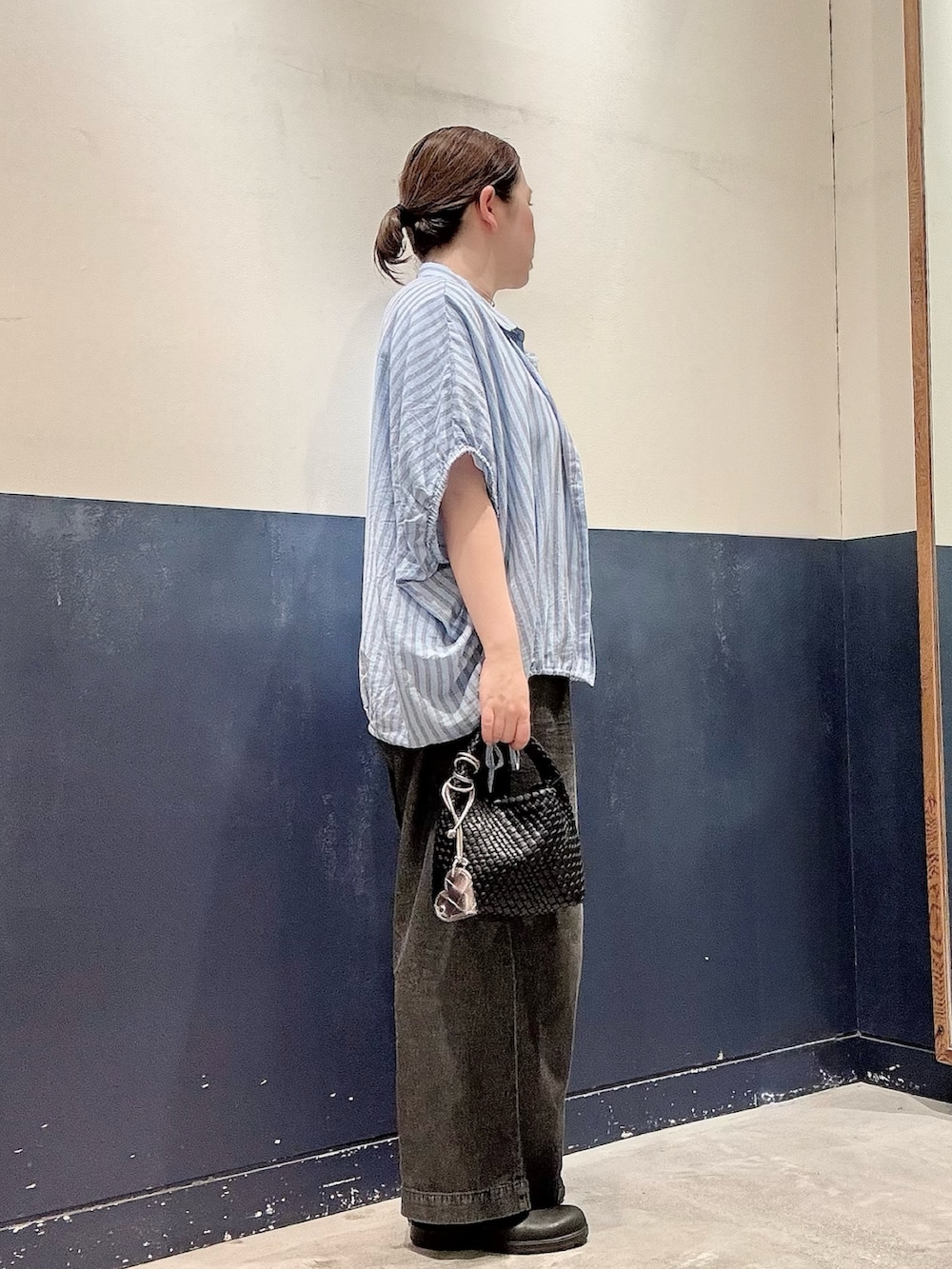 ブラック系のショルダーバッグ、ブラック系のデニムパンツ、ブルー系のシャツ/ブラウスを着用したレディースの夏コーディネートの2枚目の写真