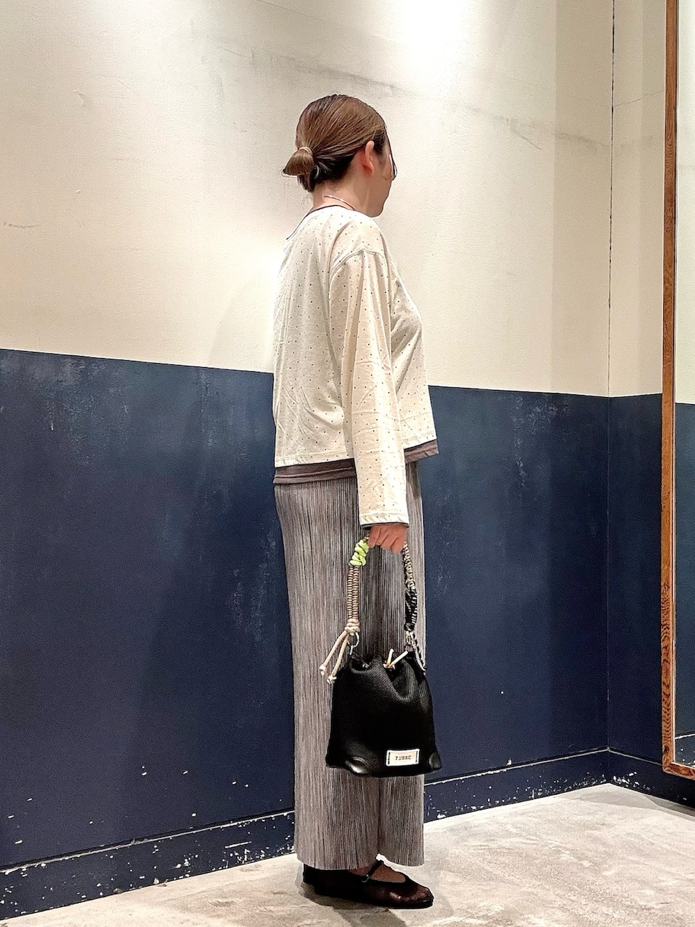 ブラック系のパンプス、ブラック系のショルダーバッグ、グレー系のスカートを着用したレディースの春コーディネートの2枚目の写真